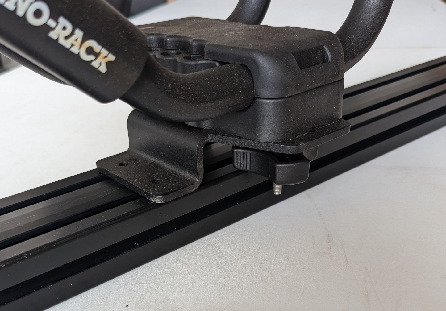 TRUKD Kayak/Gear Mount bracket seated in the T-slot crossbar channel with J-hook saddle hardware